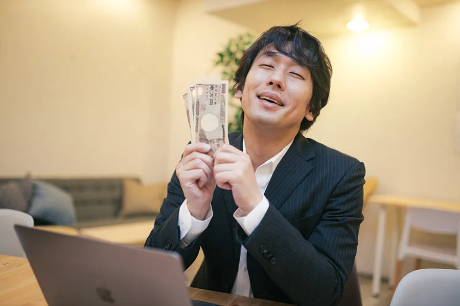 札束を握りしめる男性