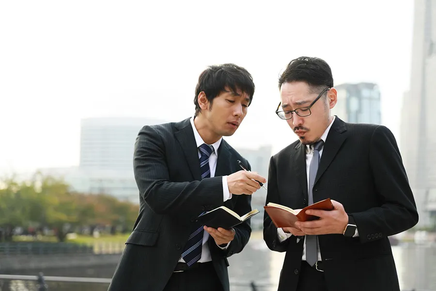 メモを確認し合う2人の男性
